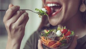 Woman eating salad mindfully at a table – practicing mindful eating for better gut health