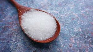 Close-up of a spoonful of white sugar – excess sugar linked to poor gut health and imbalance