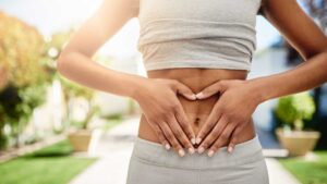 Young woman with hands placed on her stomach symbolizing a healthy gut and good digestion.