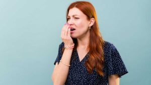 Woman covering mouth with hand – bad breath as a sign of poor gut health