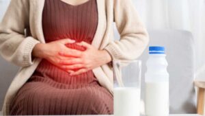 Woman holding stomach in discomfort– dairy intolerance as a sign of gut imbalance