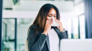 Woman sneezing into tissue – frequent illness linked to poor gut health and low immunity