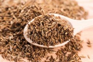 cumin seeds are a food  rich in iron on a wooden spoon – top iron-rich spices for hemoglobin